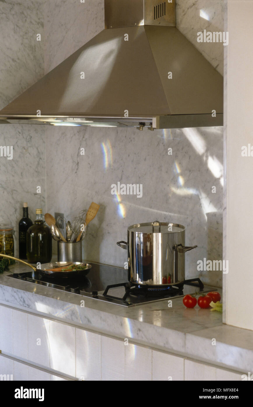 Cooking pot on gas hob set in marble kitchen worktop with cooker hood above Stock Photo Alamy