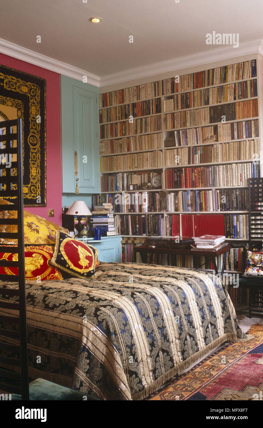 Double Bed With Stripe Cover Next To Wall Covered In Book Shelves Stock Photo Alamy