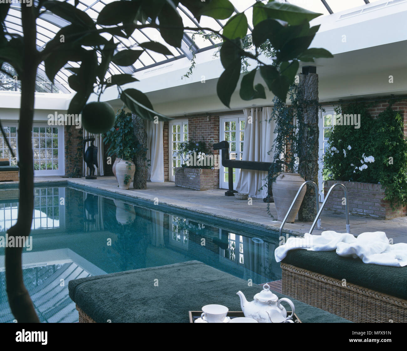 Sun loungers beside indoor swimming pool Stock Photo