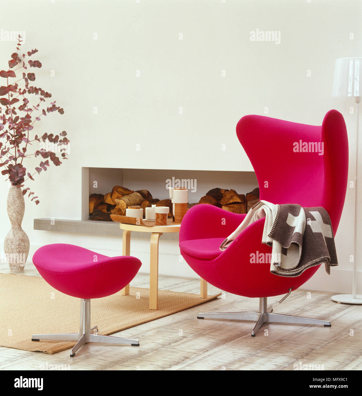 Arne Jacobsen pink chair and footstool in front of fireplace in modern sitting room Stock Photo