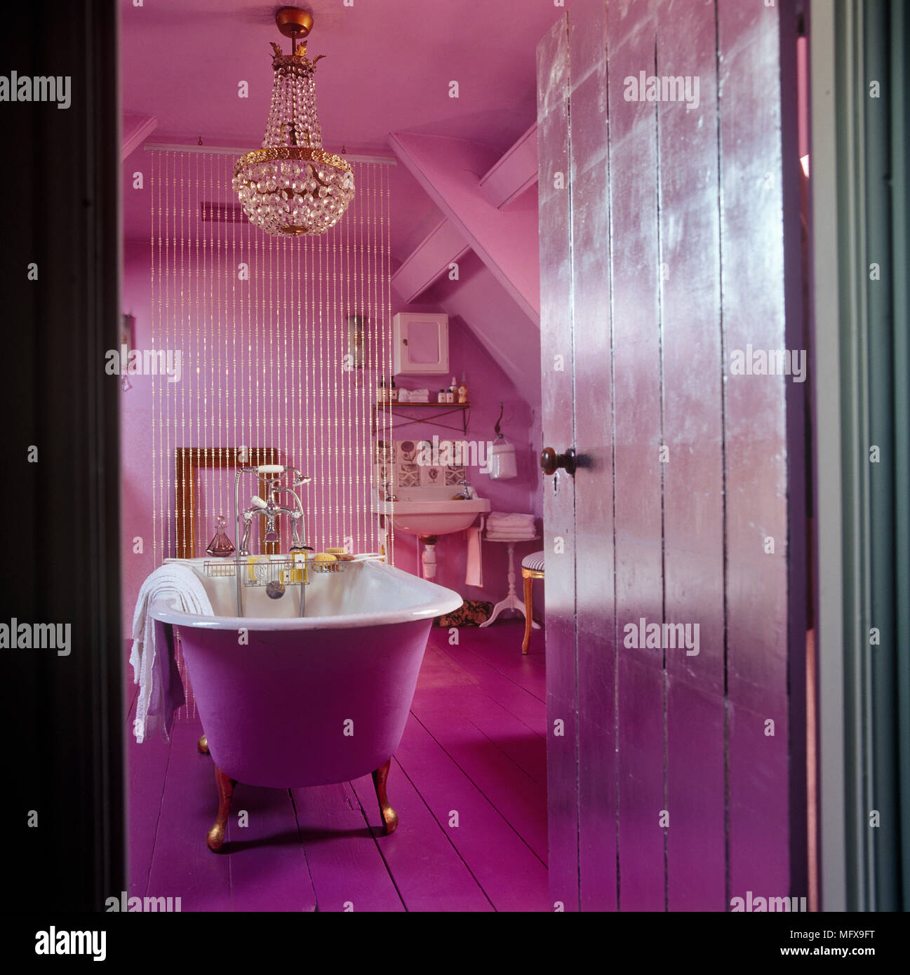 View through open door to freestanding bathtub in pink bathroom Stock