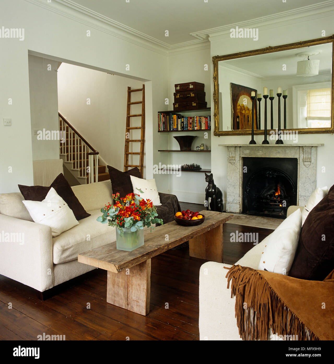 Sofas facing each other over coffee table in front of fireplace Stock