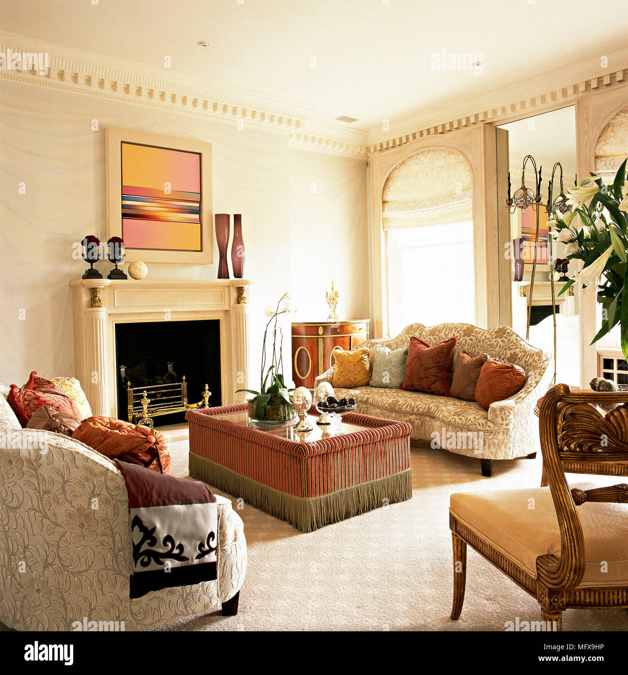 A traditional, sitting room with fireplace, ornate cornice, upholstered sofa, coffee table, carpet, Stock Photo