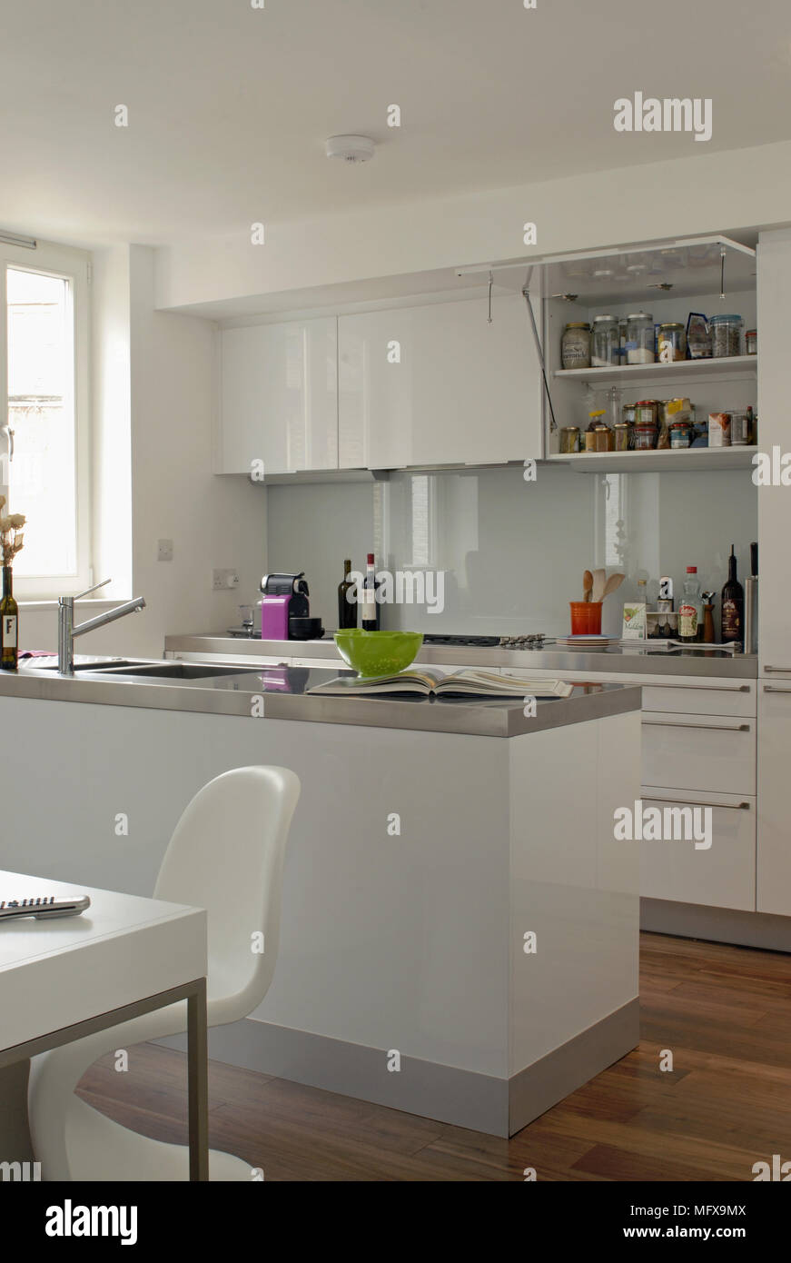 White fitted units with stainless steel worktop in contemporary kitchen ...
