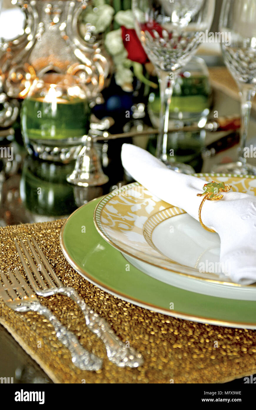 Place setting with napkin on green and gold plates Stock Photo