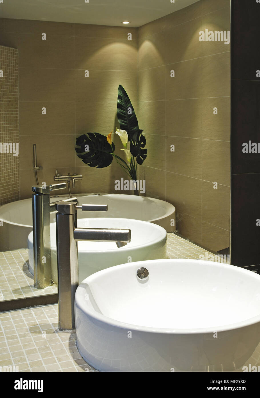 Mirror behind washbasin set on tiled shelf in modern bathroom Stock Photo