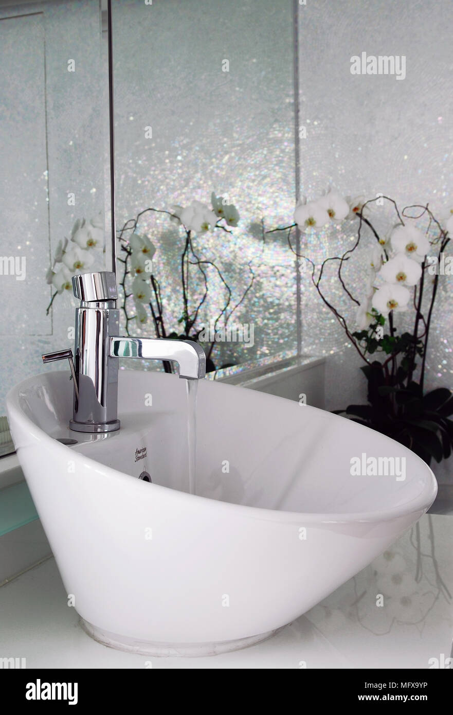 Water running from tap into bowl washbasin on modern bathroom Stock Photo