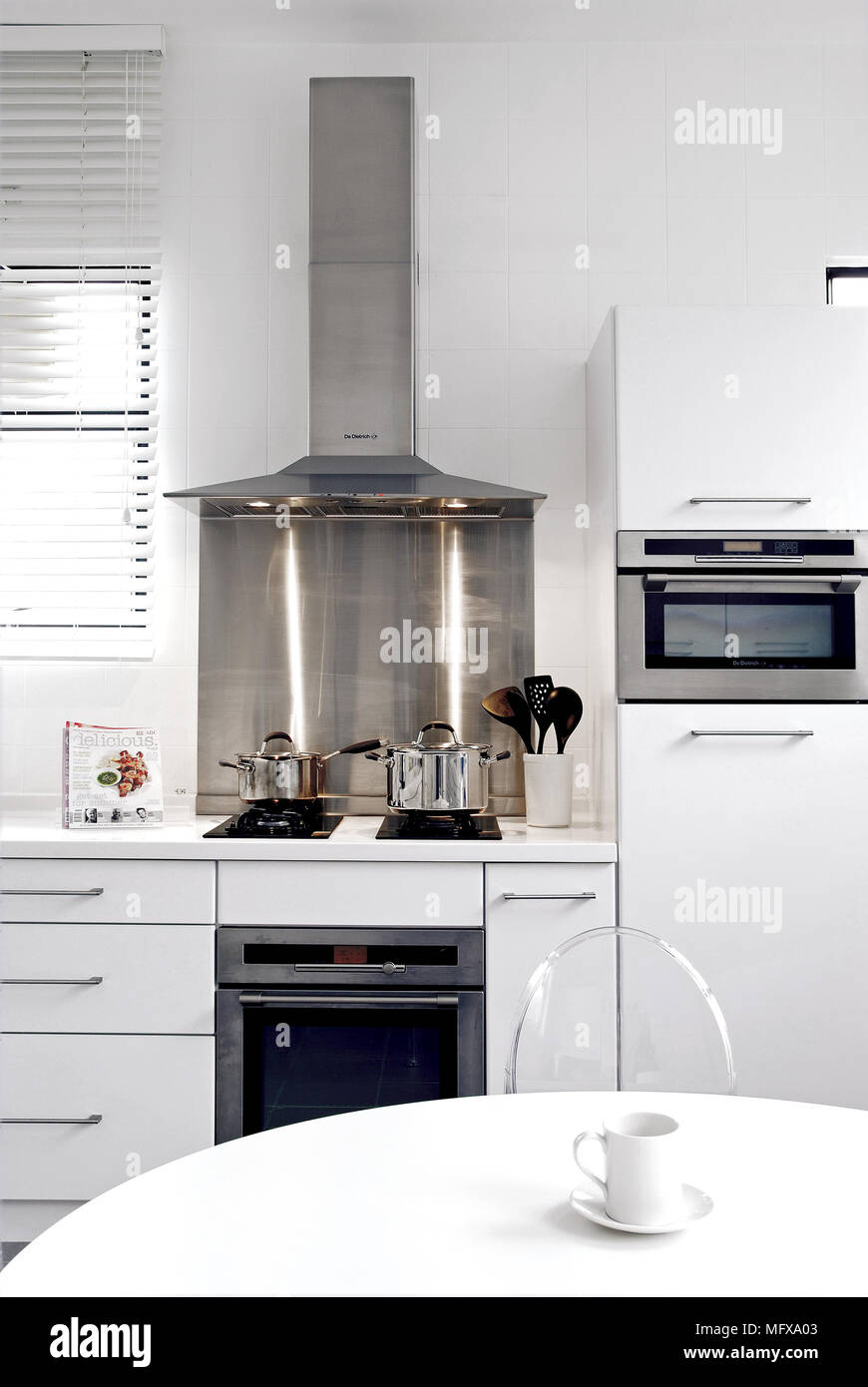 Modern kitchen with white fitted units and breakfast table Stock Photo