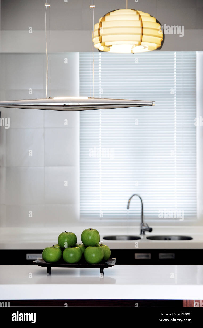Ceiling light above green apples on dish in modern kitchen Stock Photo