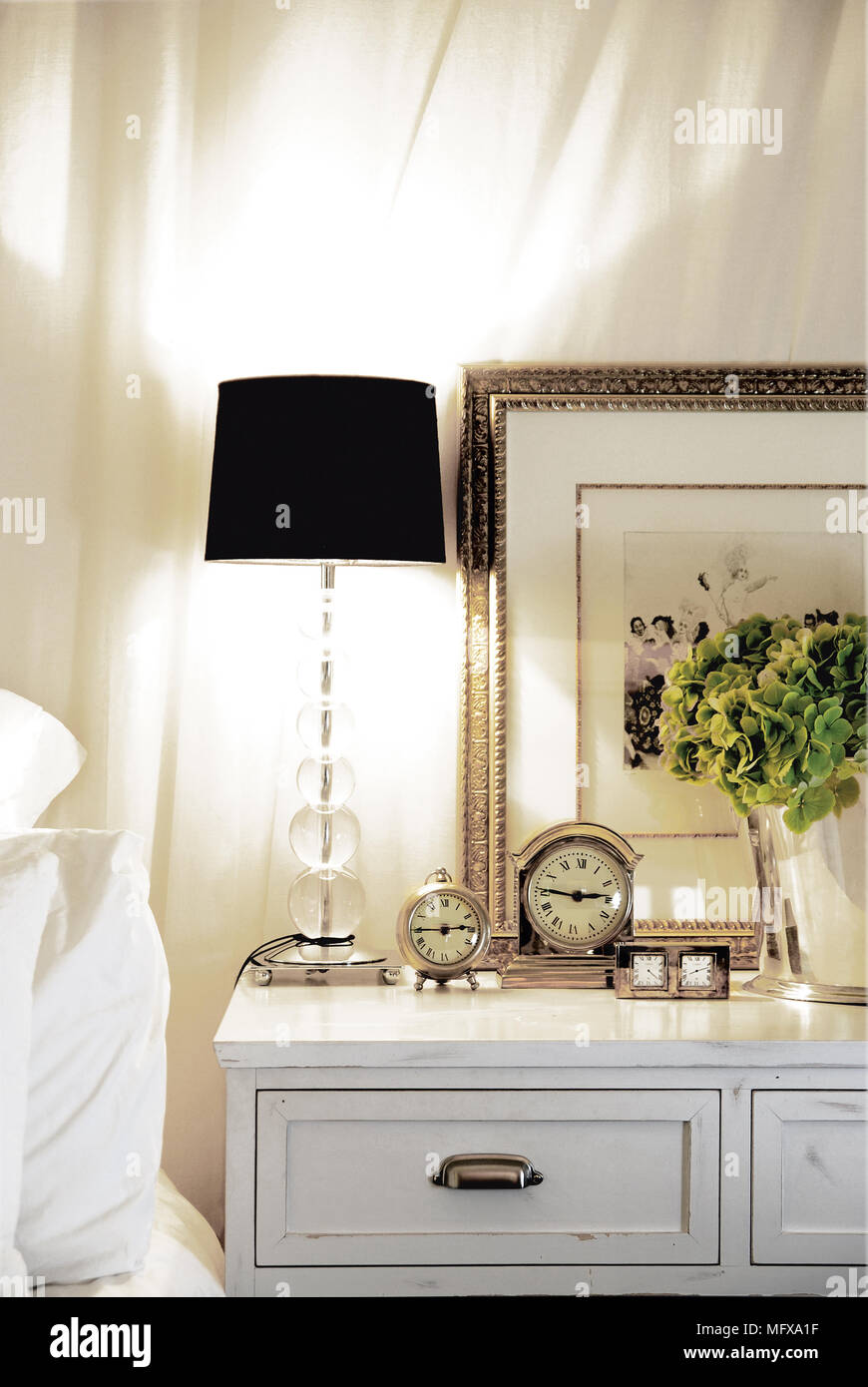 Lit lamp on bedside cabinet in traditional style bedroom Stock Photo