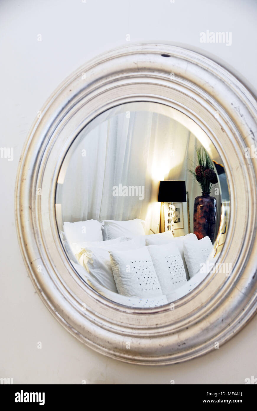 Cushions on bed reflected in round mirror Stock Photo