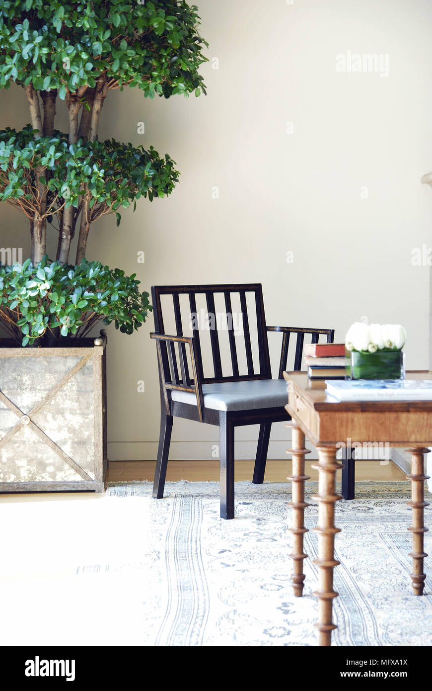 Wooden chair and table next to tree in planter Stock Photo