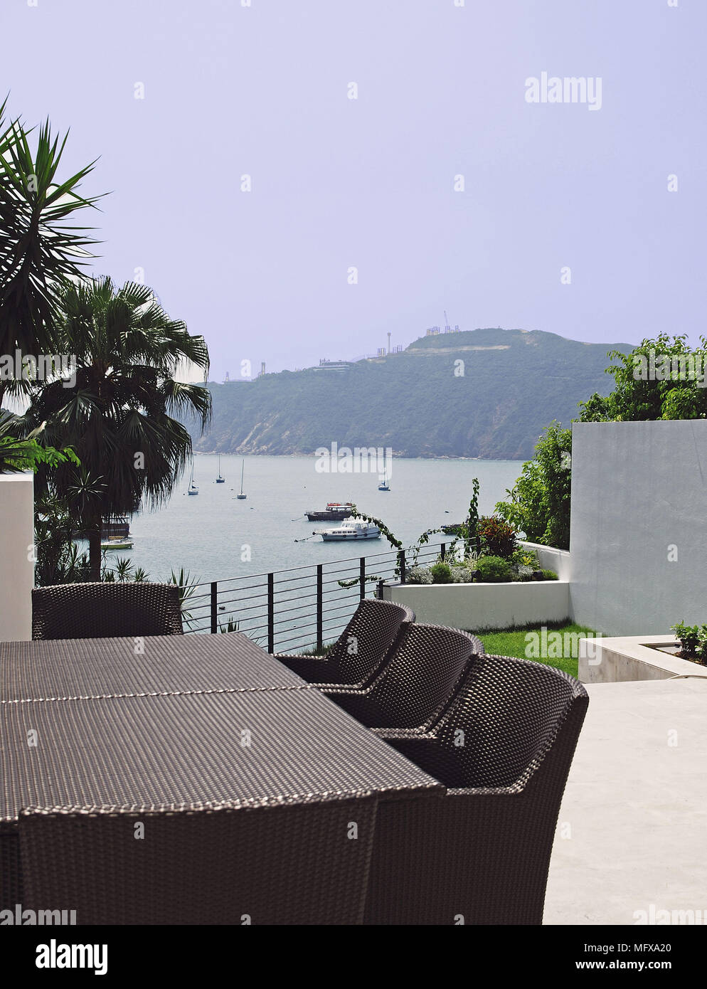 Cane table and chairs on terrace overlooking harbour Stock Photo