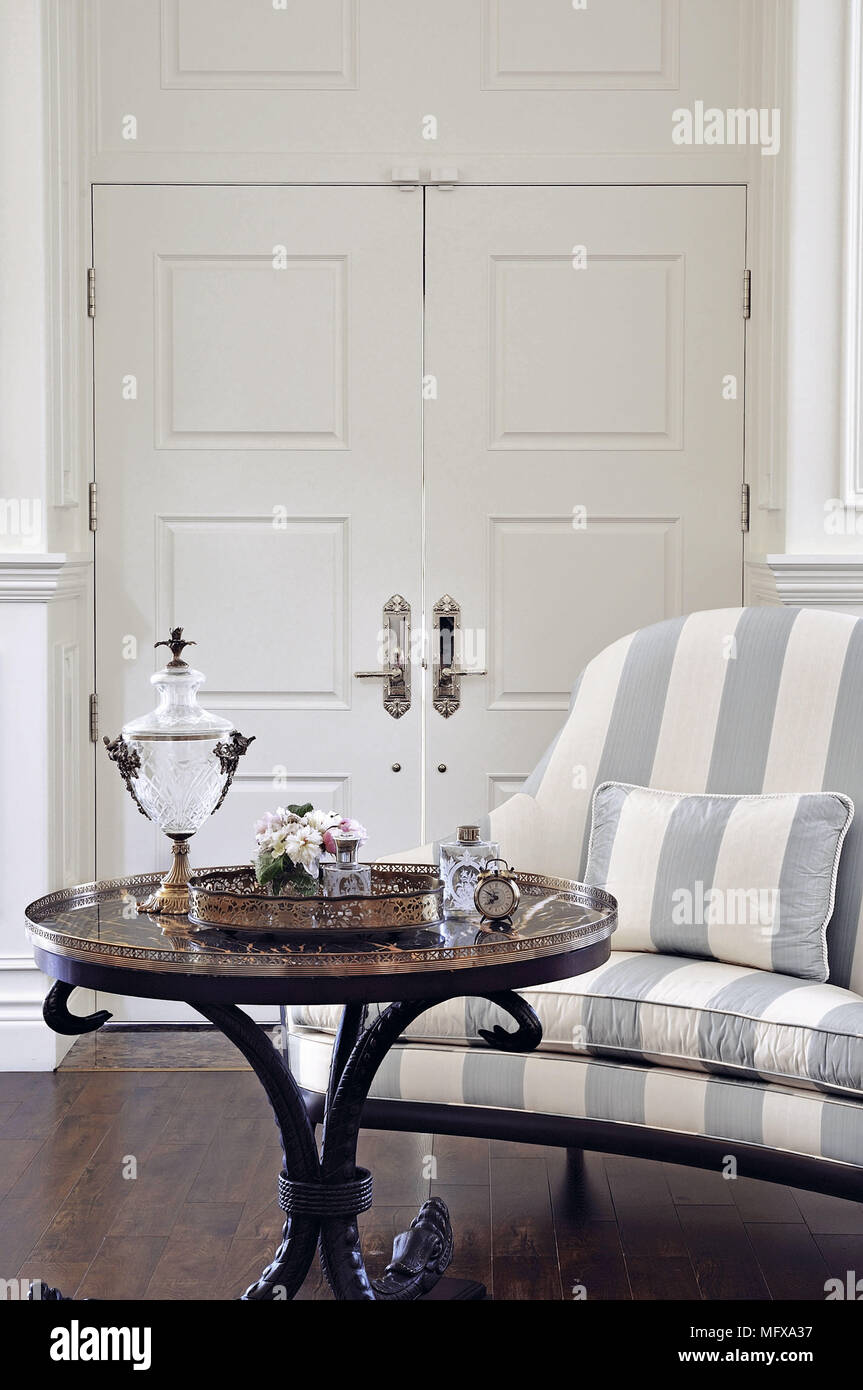 Items on round table in front of upholstered chair with stripe pattern fabric Stock Photo