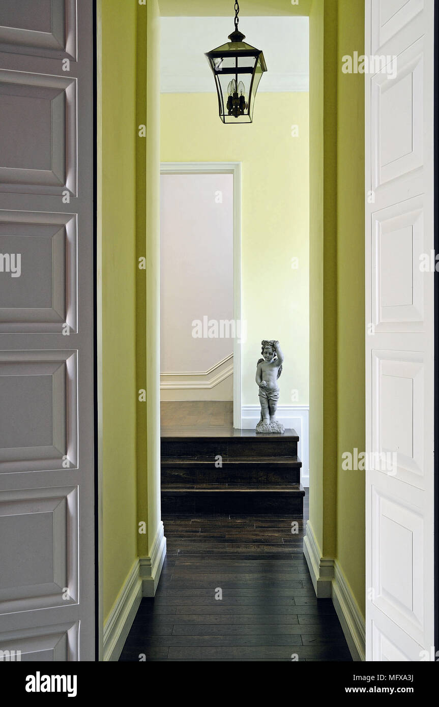 View along narrow corridor to statue on steps Stock Photo