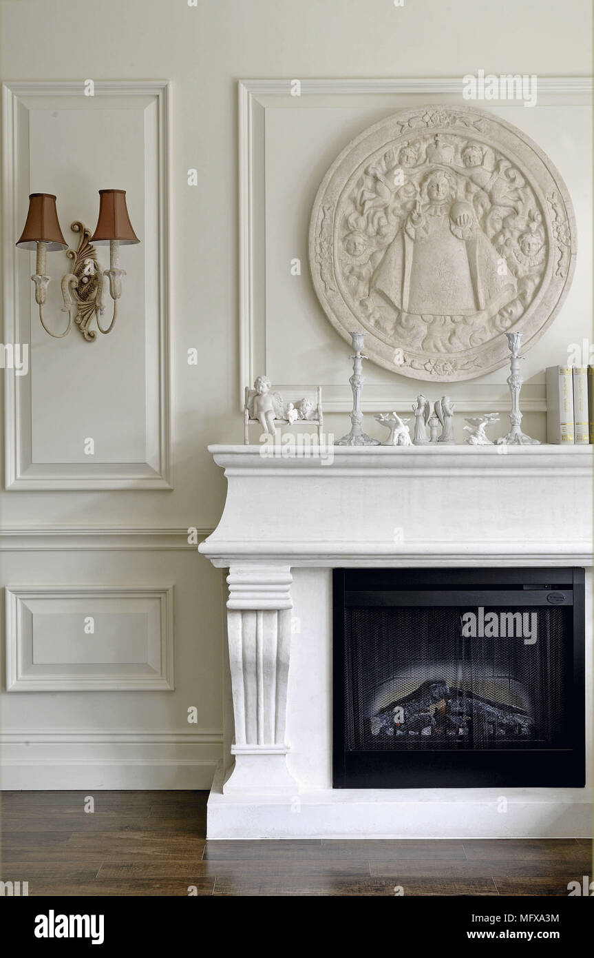 Ornate plaster plaque on wall above fireplace in traditional style room Stock Photo