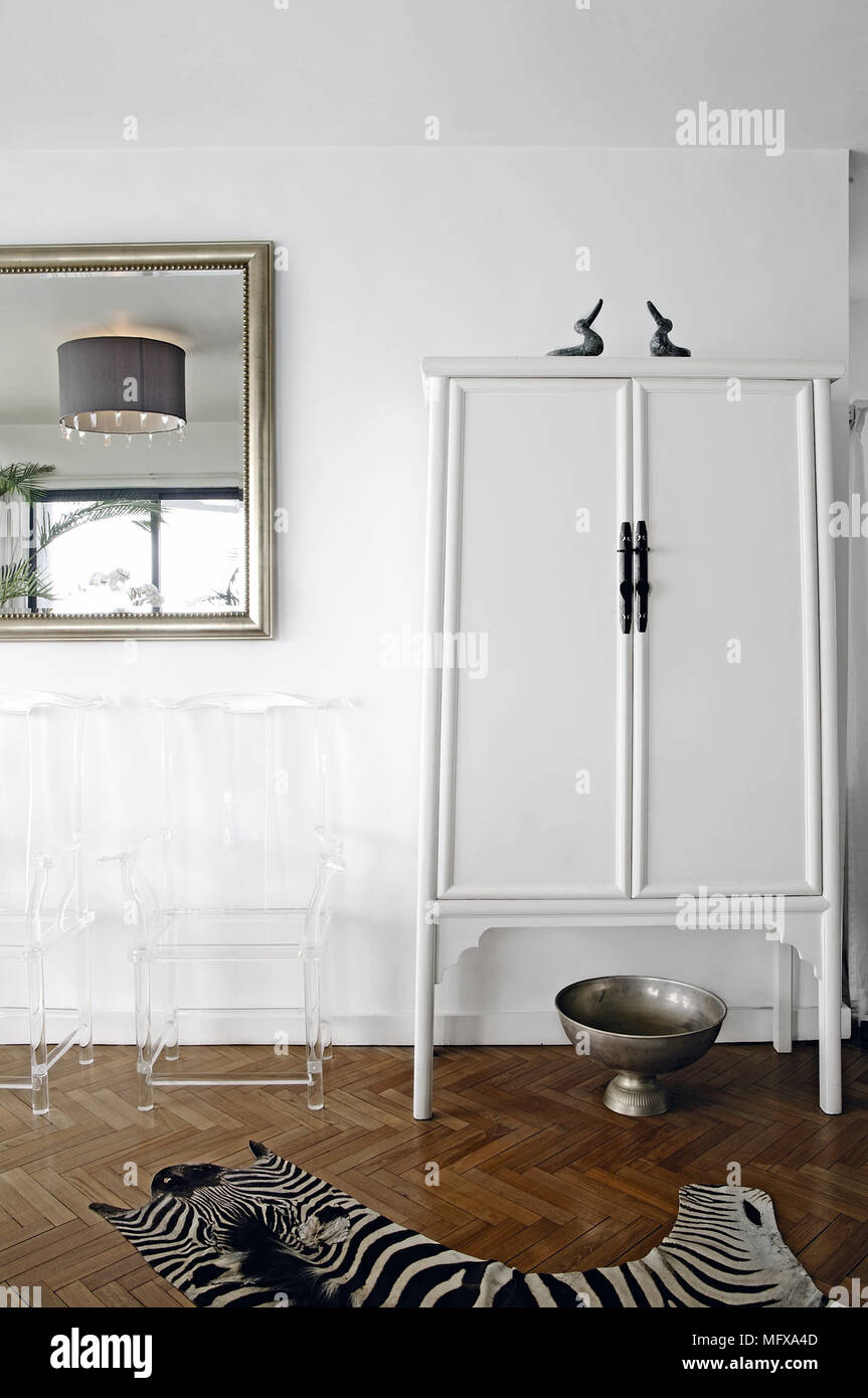 Clear plastic chairs next to modern cabinet in white room Stock Photo