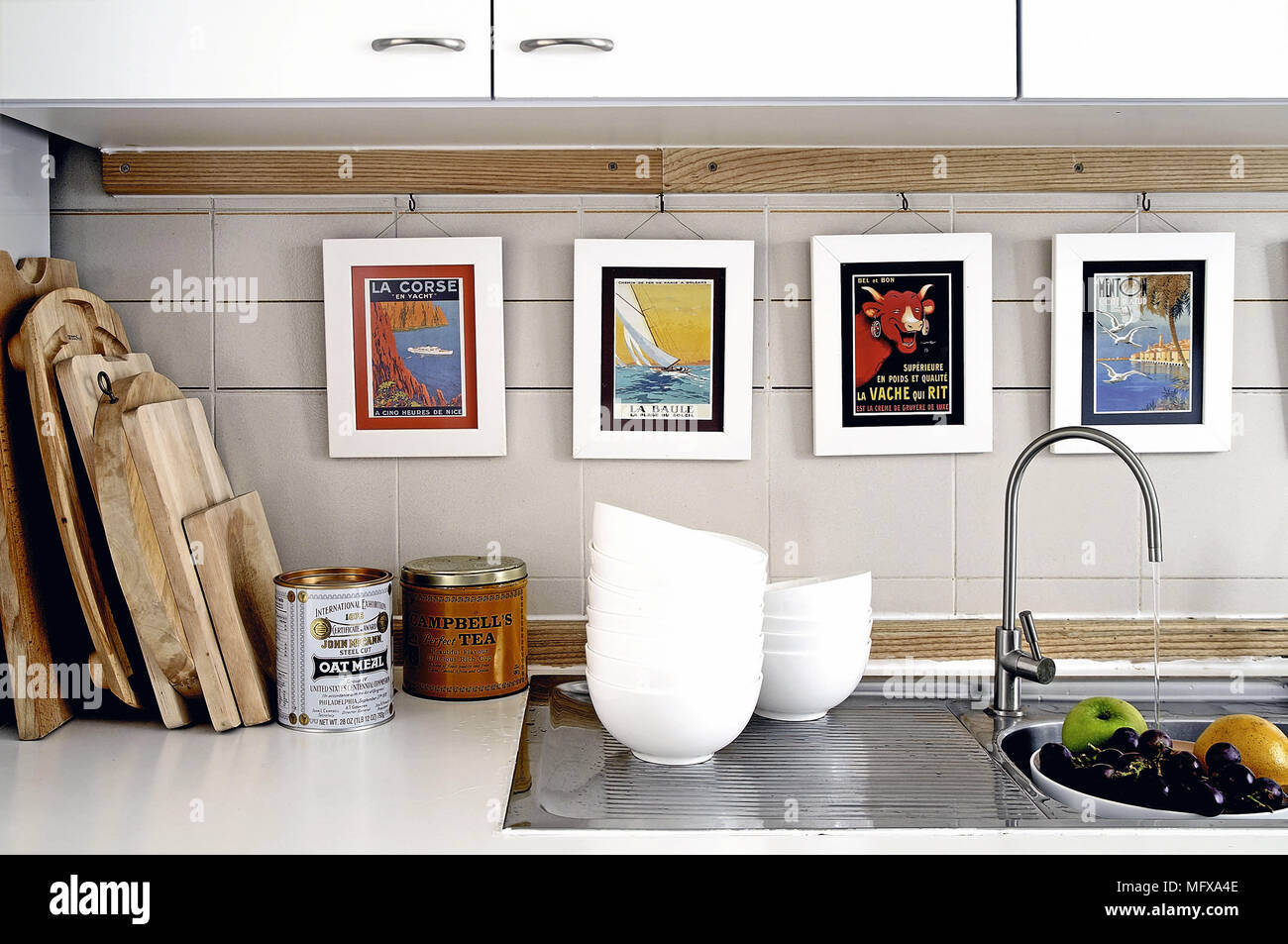 Water running from tap fitting onto bowl of fruit in kitchen sink Stock Photo