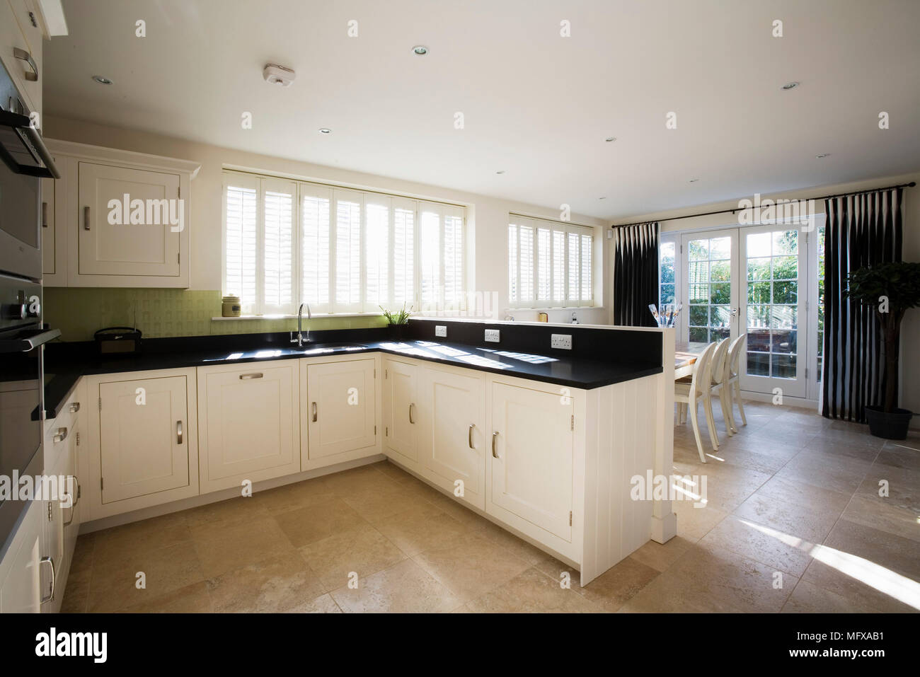 Spacious kitchen with white units and dining area Stock Photo