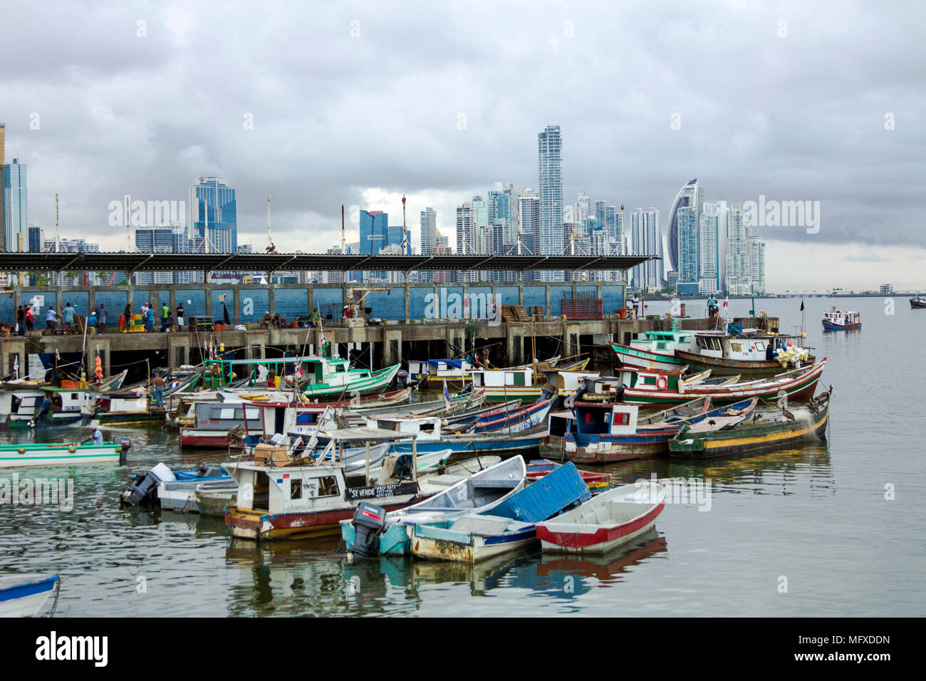 Colourful fishing boats anchored at the fish market in Panama City, Panama, with the city's modern high rises in the background Stock Photo