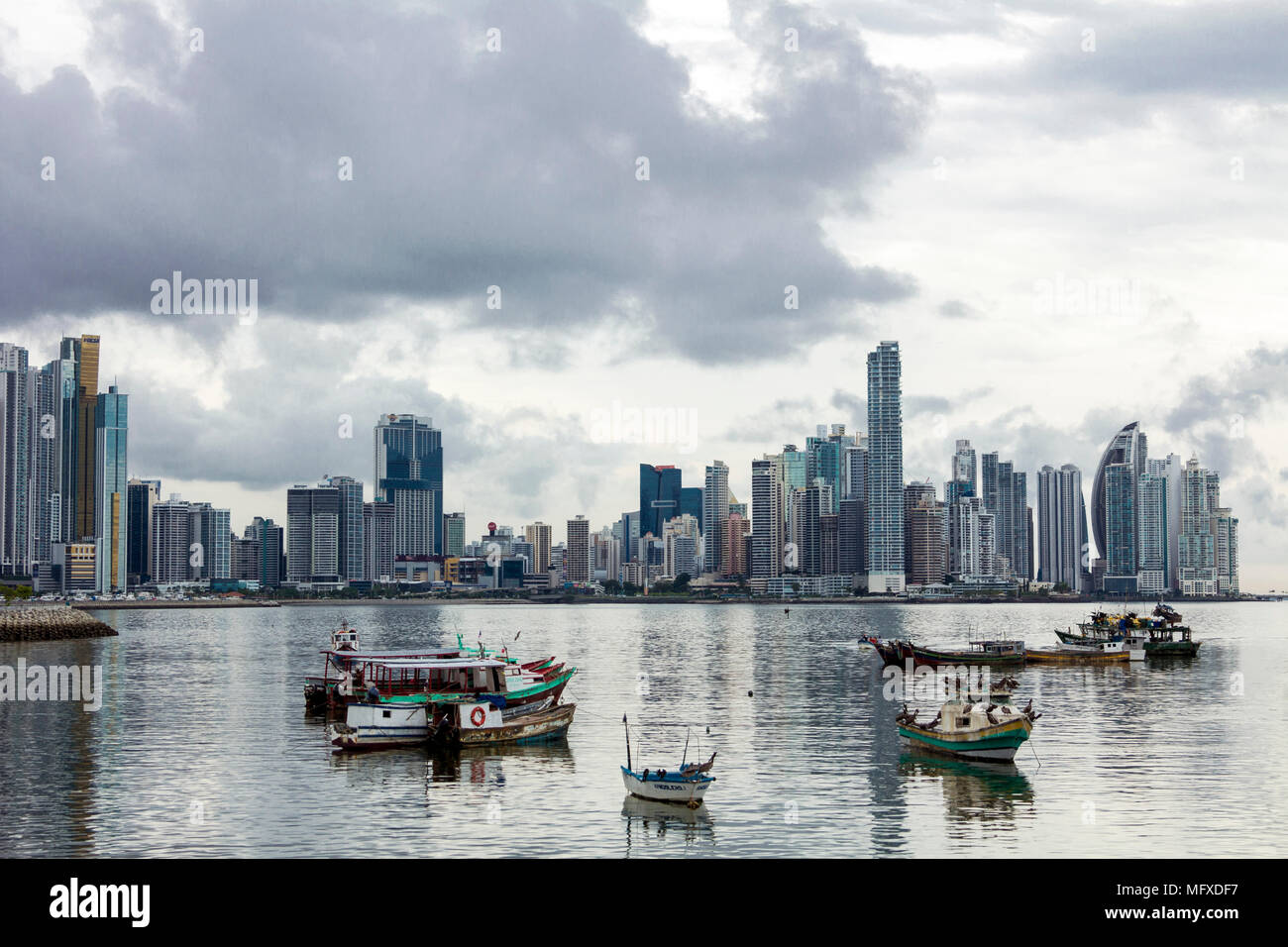 The Panama City, Panama, skyline of modern high rises contrasts with the small fishing boats in the foreground at the city's fish market Stock Photo