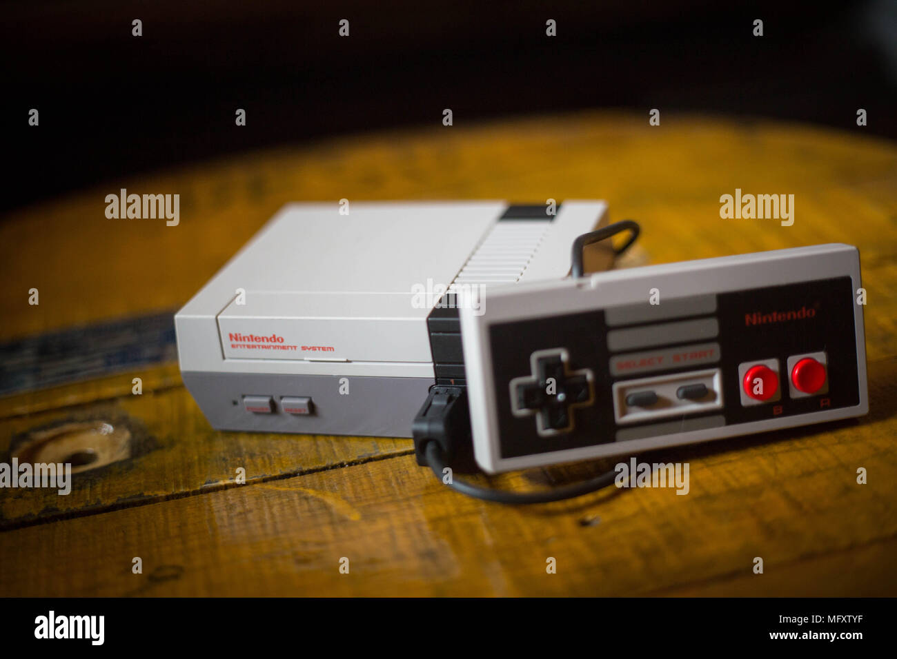 A Nintendo Classic Mini 'Nintendo Entertainment System' video game console with a controller plugged on it. The Kyoto based video game company Nintendo ended it’s comeback year revenue with worth $9 Billion after a glorious year 2017 notably with the launch of the hybrid console the Nintendo Switch, mini retro vintage game consoles such as the Nintendo Entertainment System and Super Nintendo as well as its mobile phone video games. Stock Photo