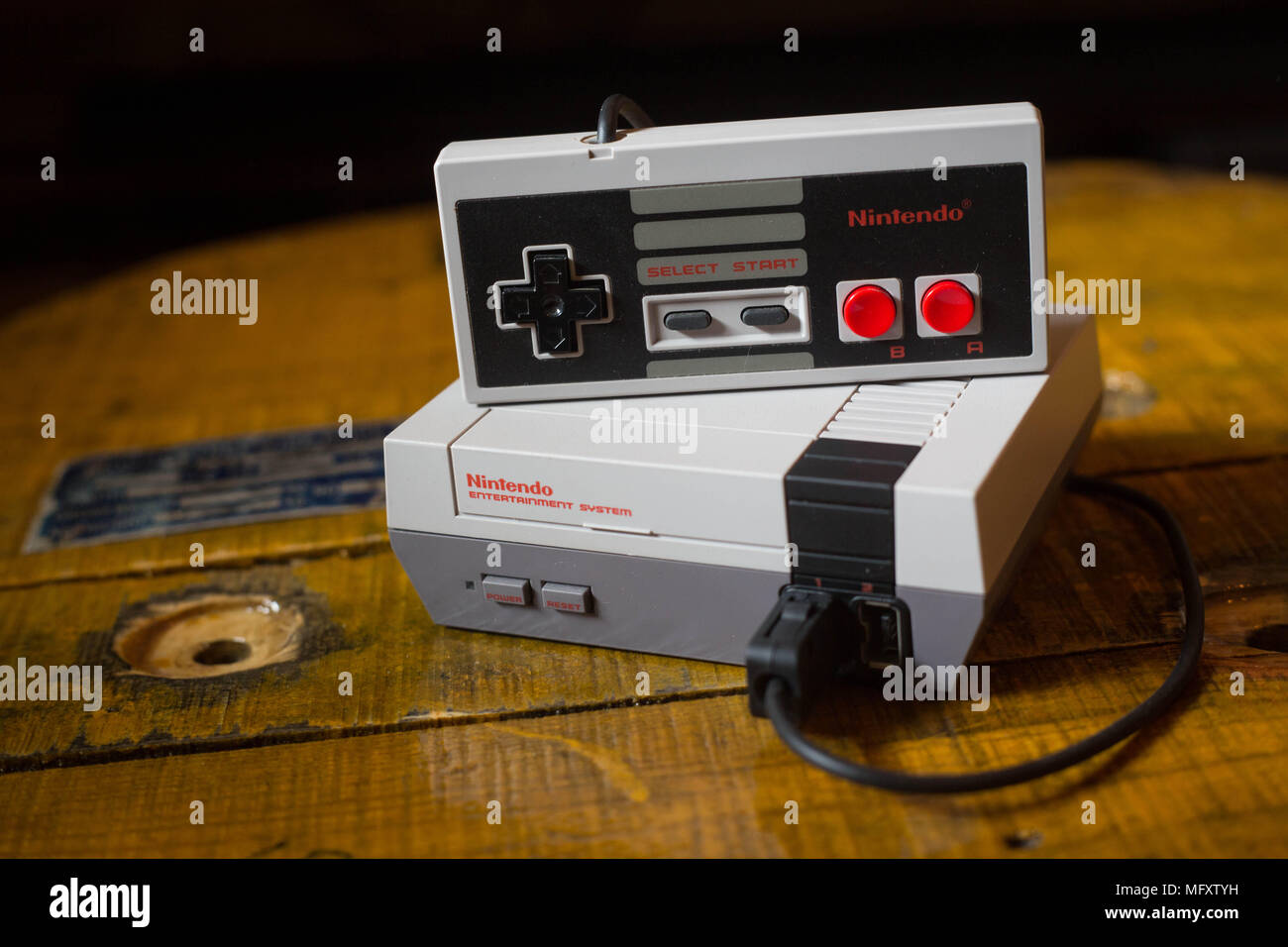 A Nintendo Classic Mini 'Nintendo Entertainment System' video game console with a controller plugged on it. The Kyoto based video game company Nintendo ended it’s comeback year revenue with worth $9 Billion after a glorious year 2017 notably with the launch of the hybrid console the Nintendo Switch, mini retro vintage game consoles such as the Nintendo Entertainment System and Super Nintendo as well as its mobile phone video games. Stock Photo