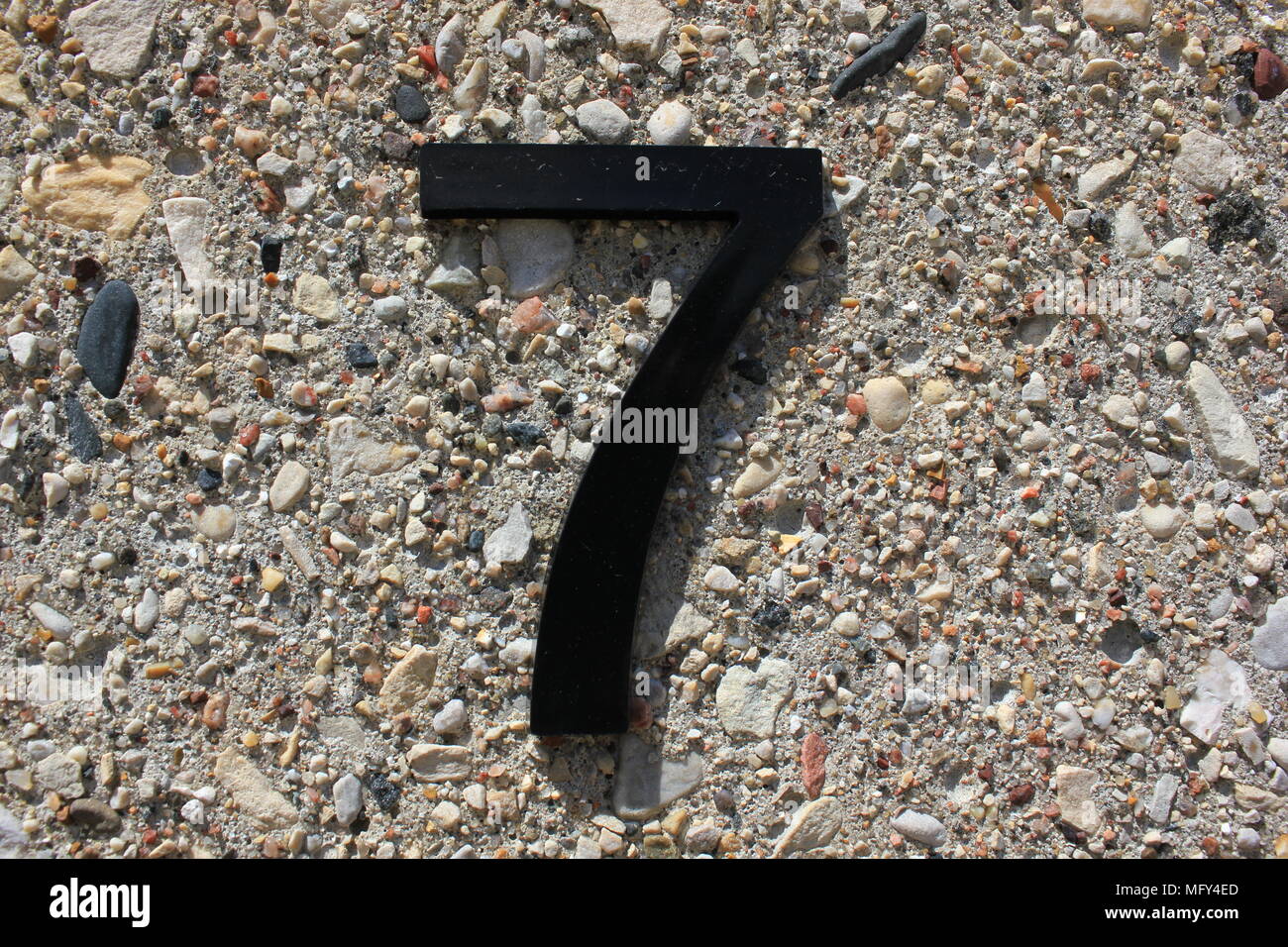 The number seven as a black plastic text glued to a textured pebble