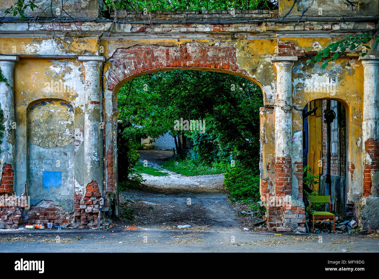 Picturesque old broken brick arch in the town yard Stock Photo