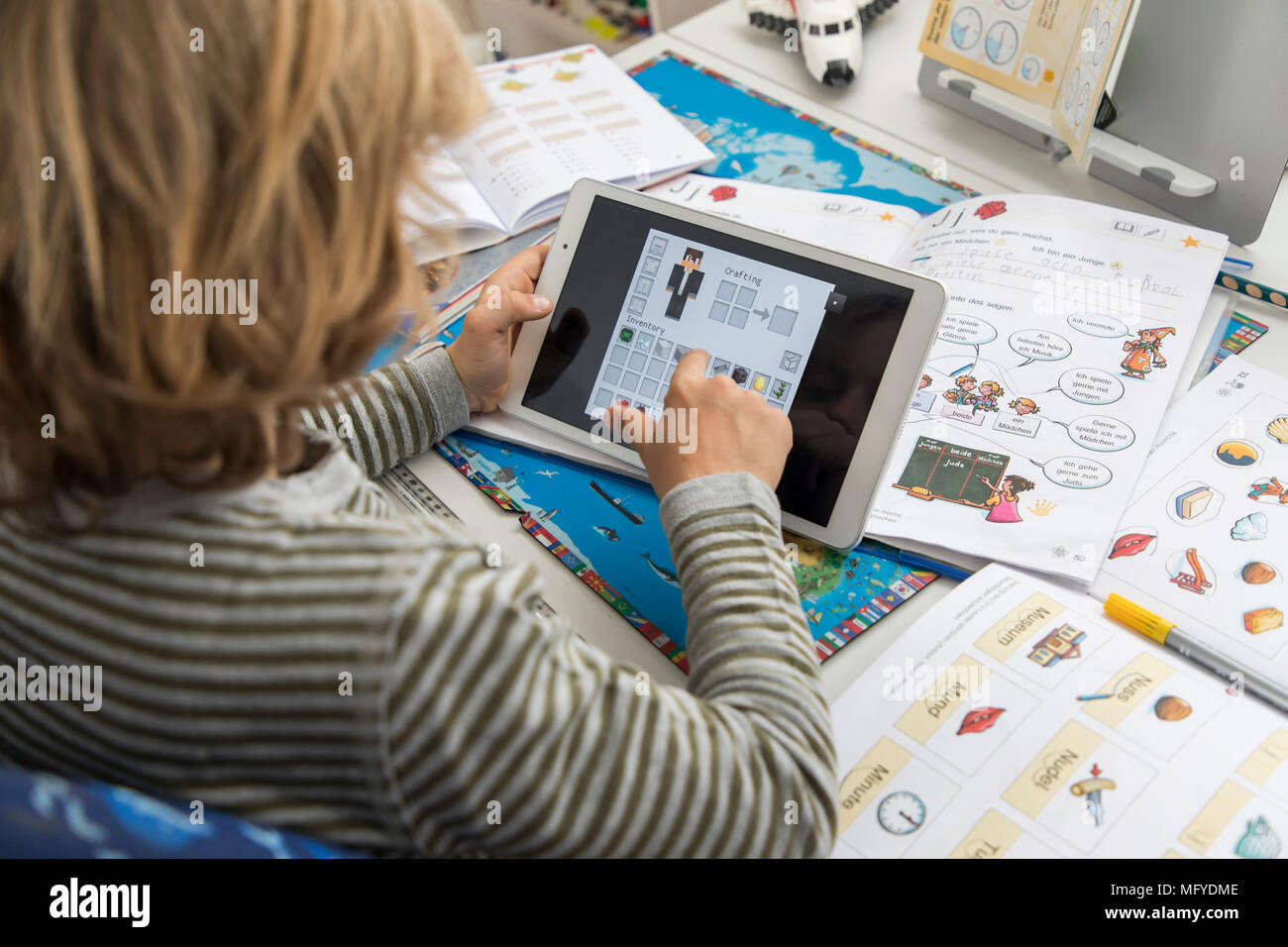 Boy, elementary school student, 8 years old, learns for school at home, does homework, uses a tablet computer for learning, Stock Photo