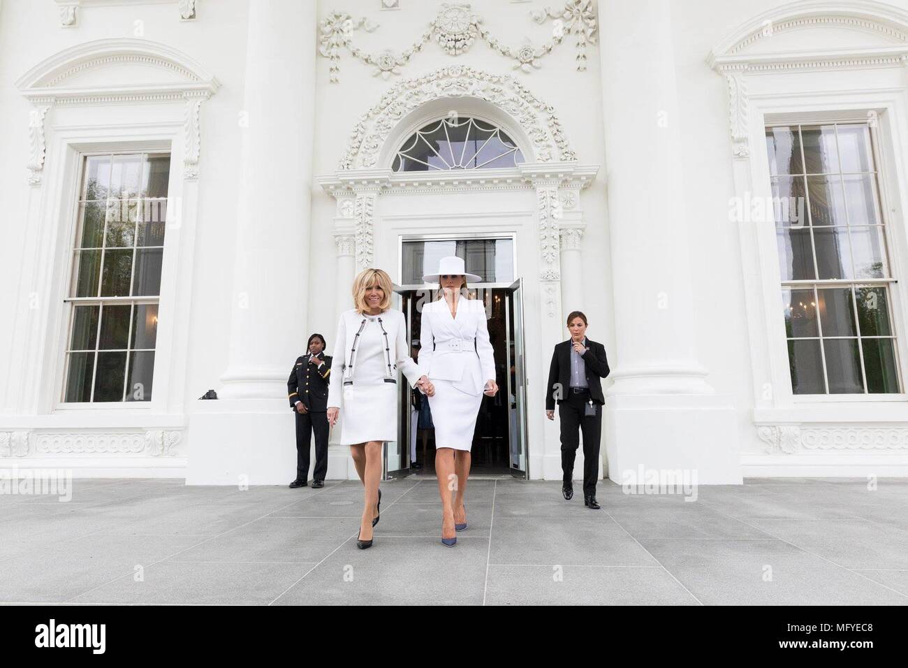 U.S. First Lady Melania Trump walks holding hands with Brigitte Macron, wife of French President Emmanuel Macron on the South Lawn for the State Visit arrival ceremony at the White House April 24, 2018 in Washington, DC. Stock Photo