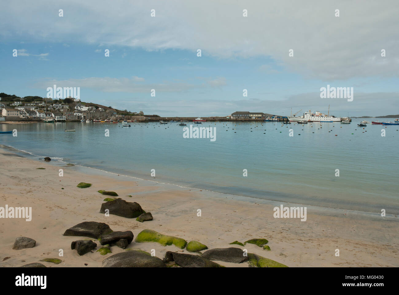 View across St Mary's Harbour, Isles of Scilly showing Town Beach with the Scillonian ferry moored at the quayside. Pale blue morning light. Stock Photo