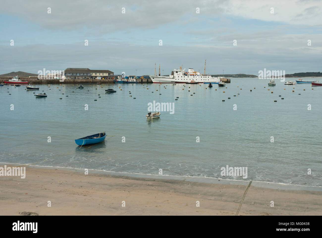 View across St Mary's Harbour, St Mary's, Isles of Scilly from Town Beach with the Scillonian ferry moored at the quayside. Pale blue morning light. Stock Photo
