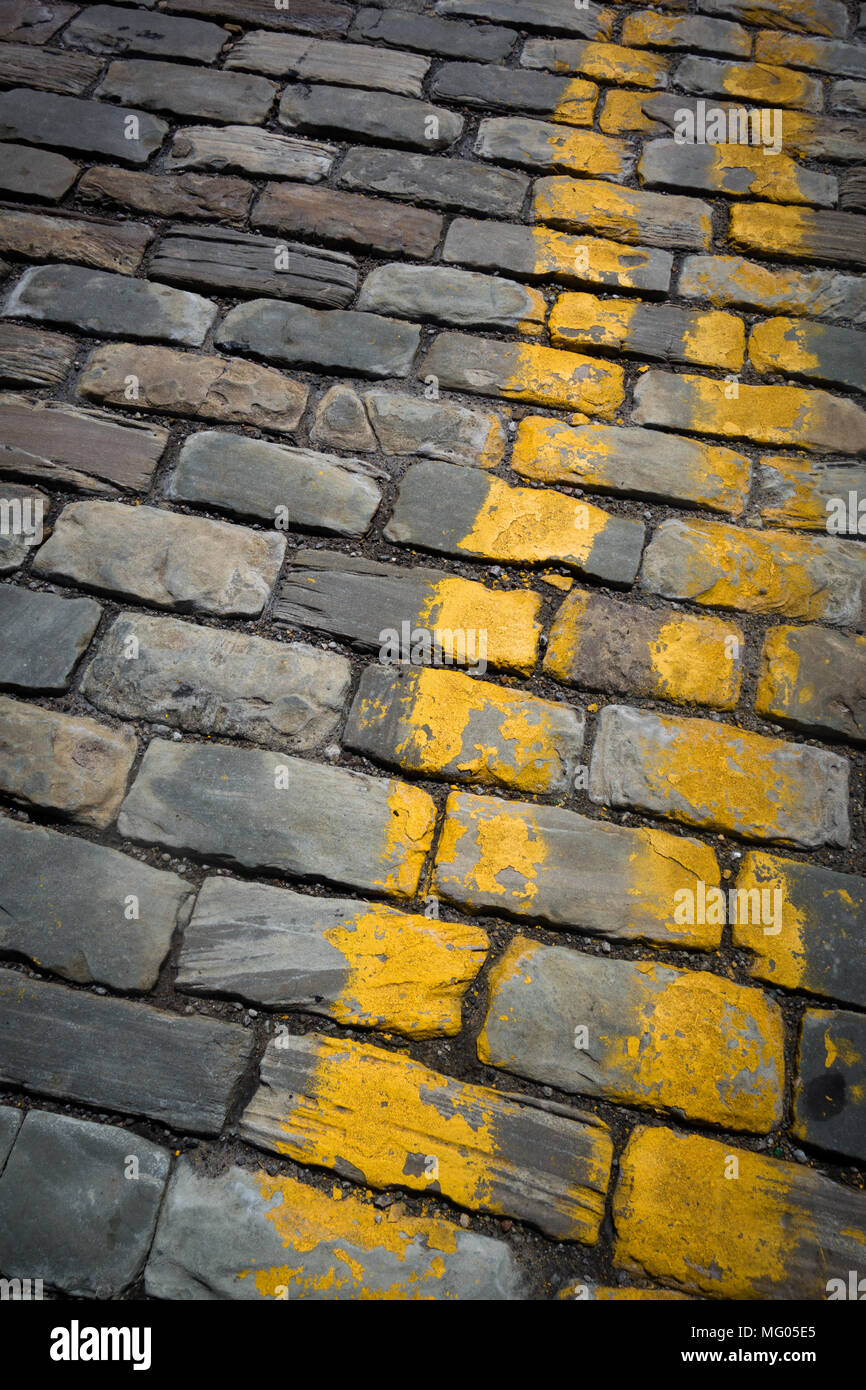 Yellow stripes painted on a cobblestone roadway Stock Photo