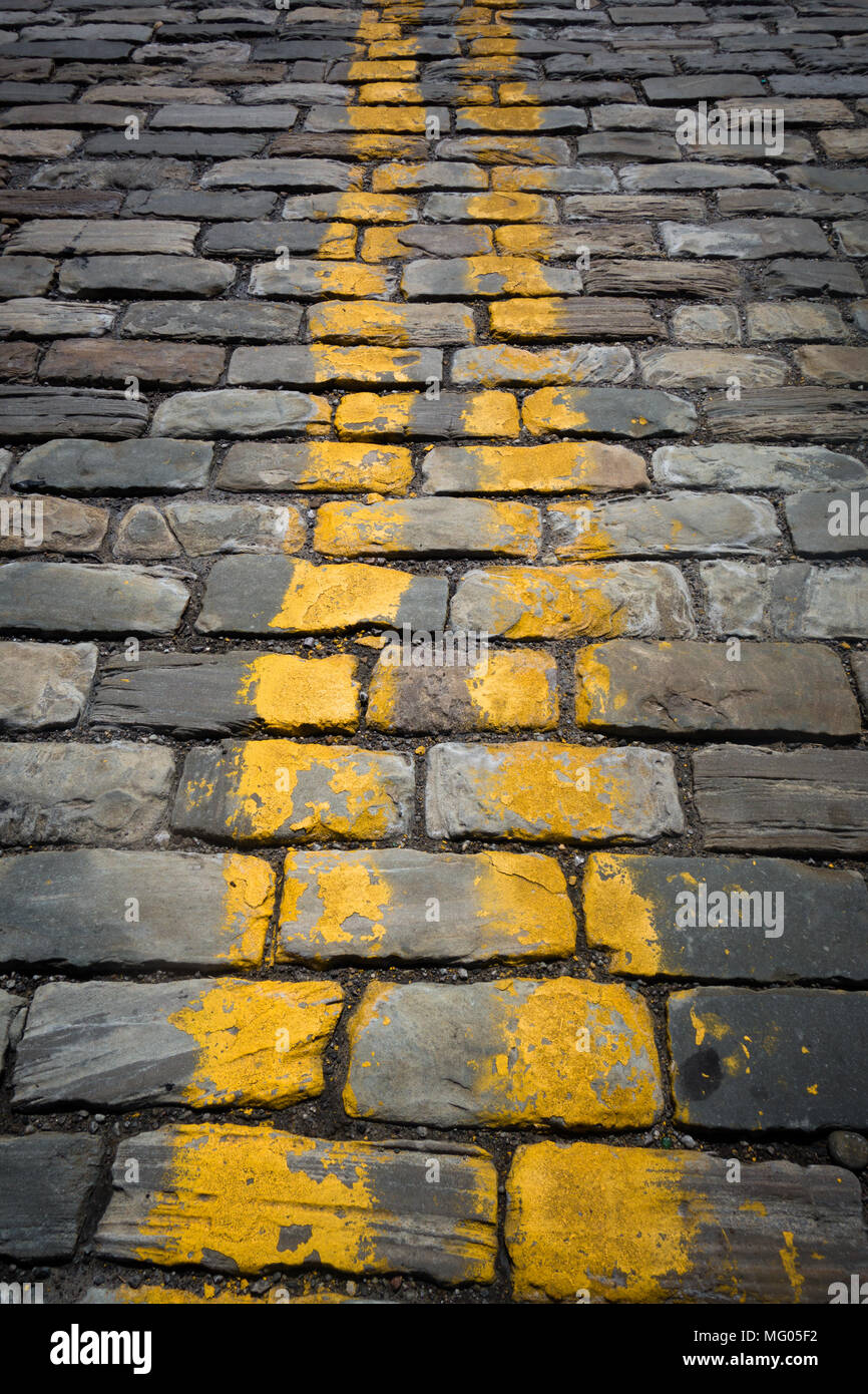 Yellow stripes painted on a cobblestone roadway Stock Photo