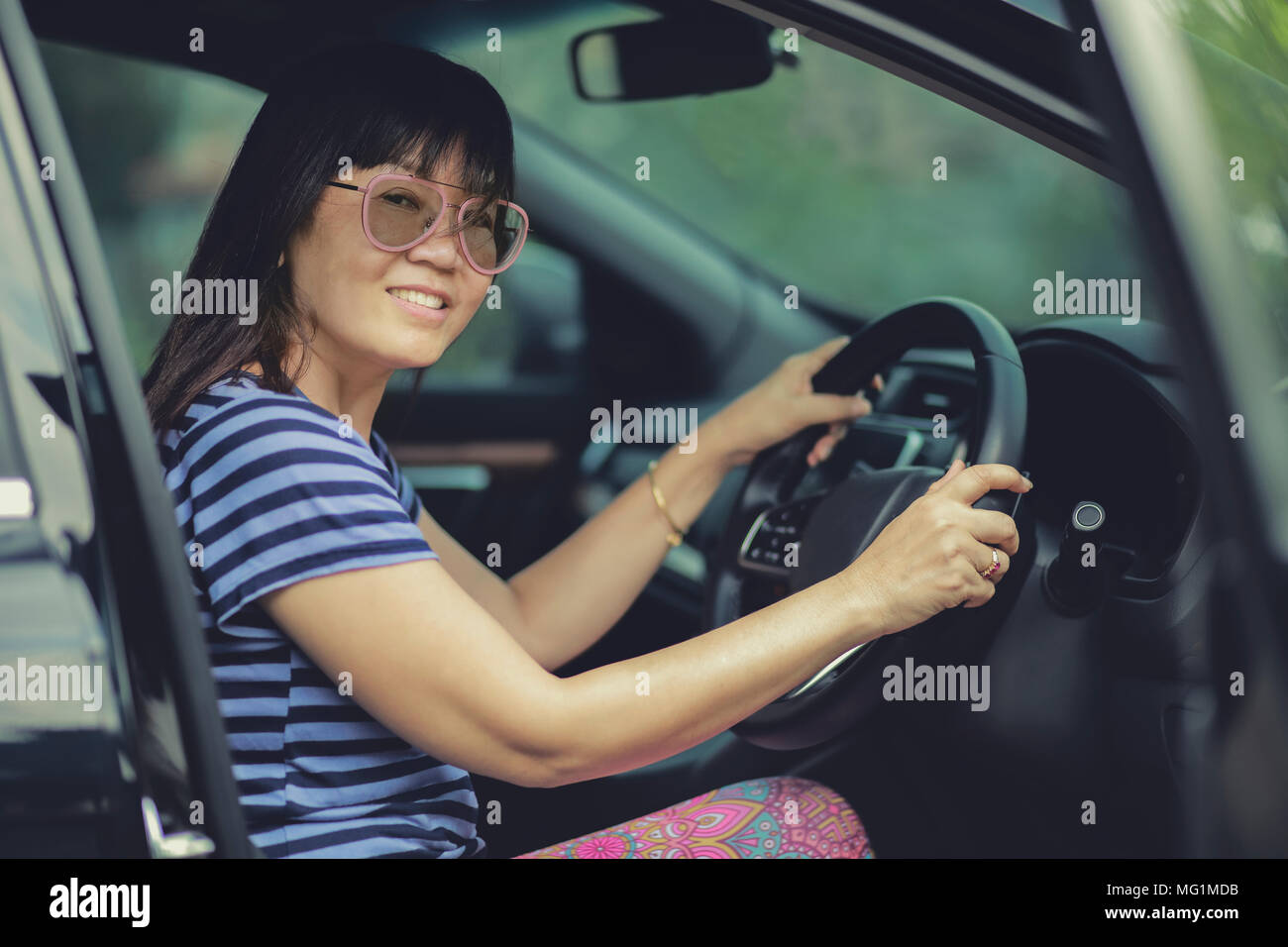 asian woman sitting on driver seat and toothy smiling Stock Photo