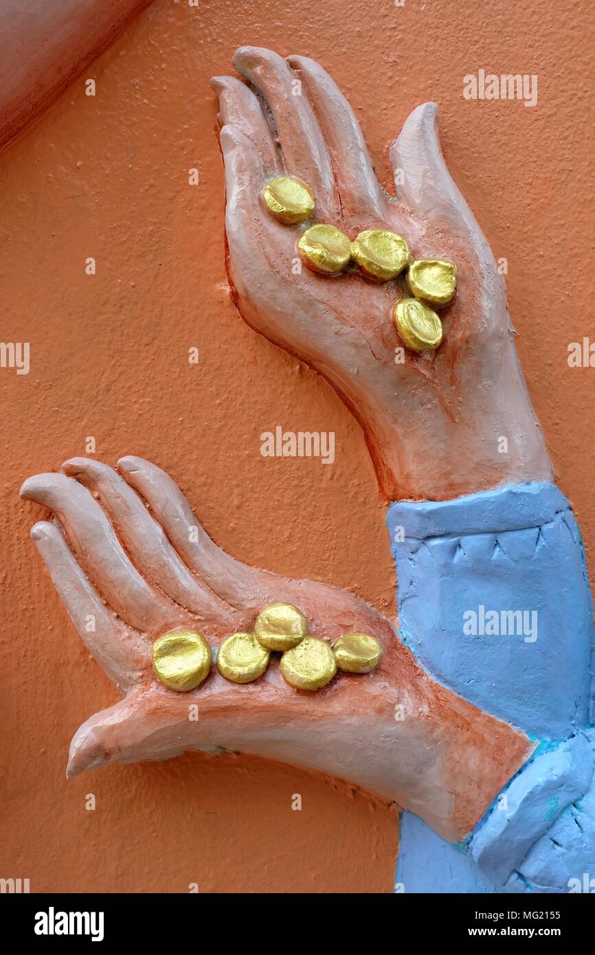 Close up Golden Coins in Sculpture Hand on Concrete Wall Stock Photo