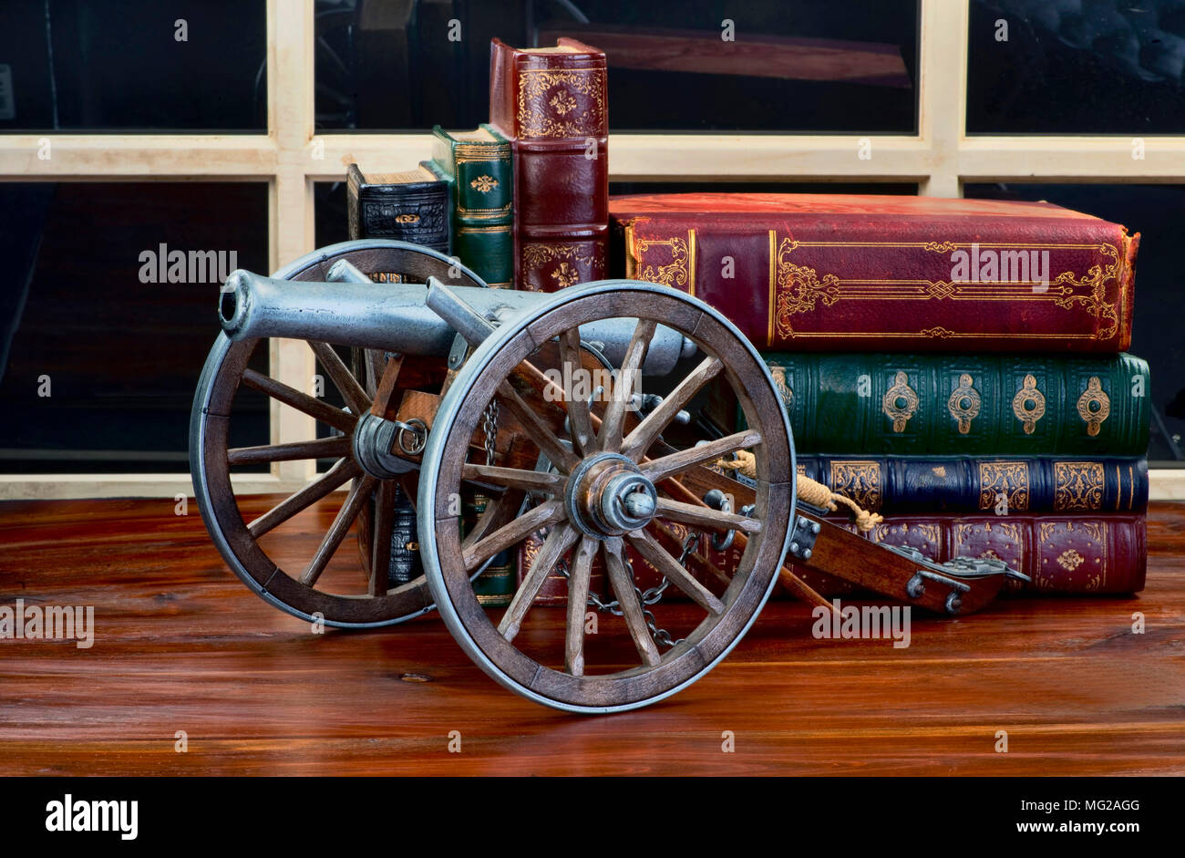 Old American cannon model with antique books in background. Stock Photo