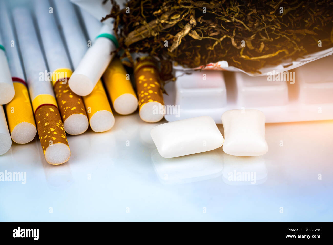 Nicotine chewing gum near pile of cigarettes and tobacco on white