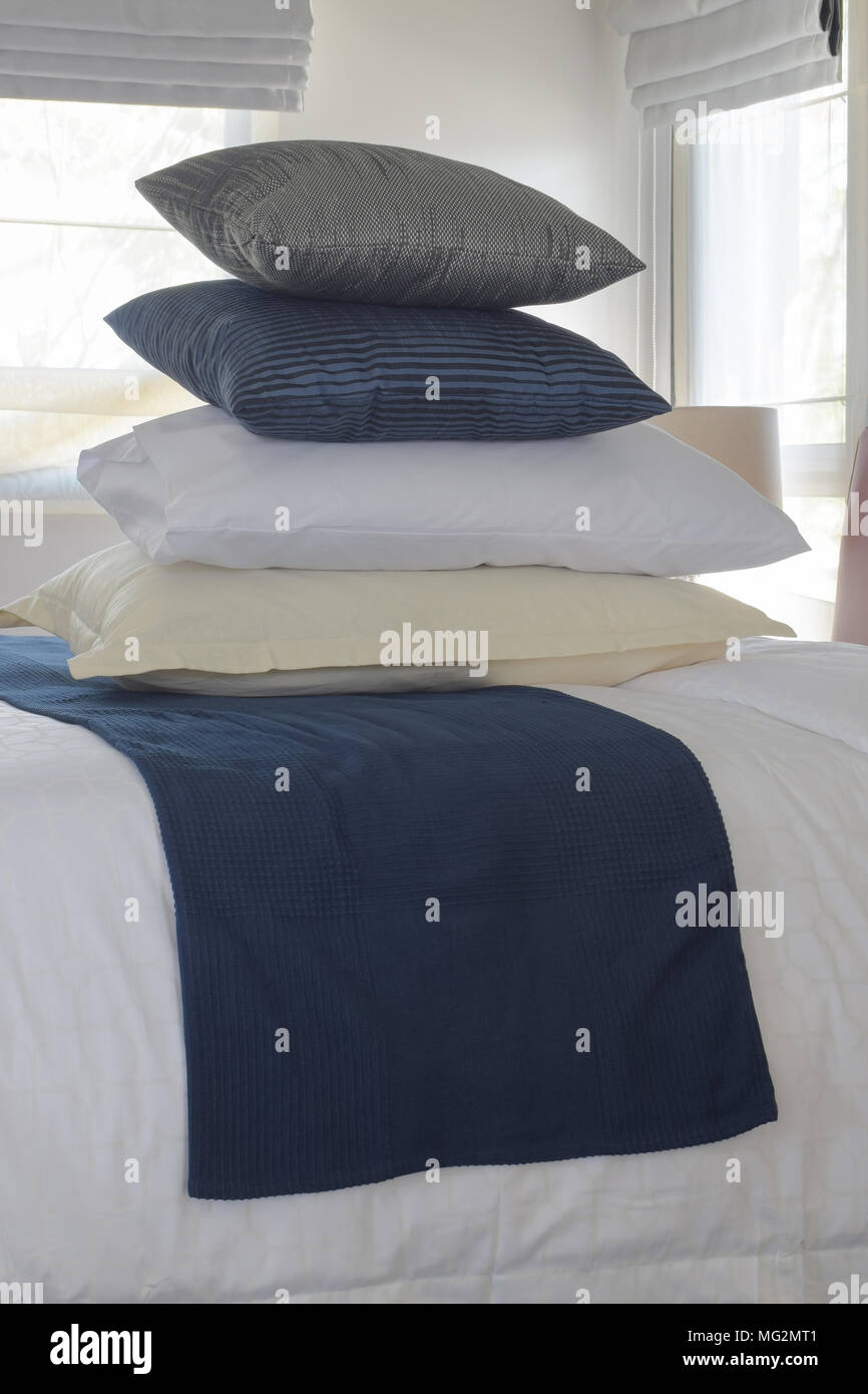 Stacking pillows on bed with wall and window in background Stock Photo