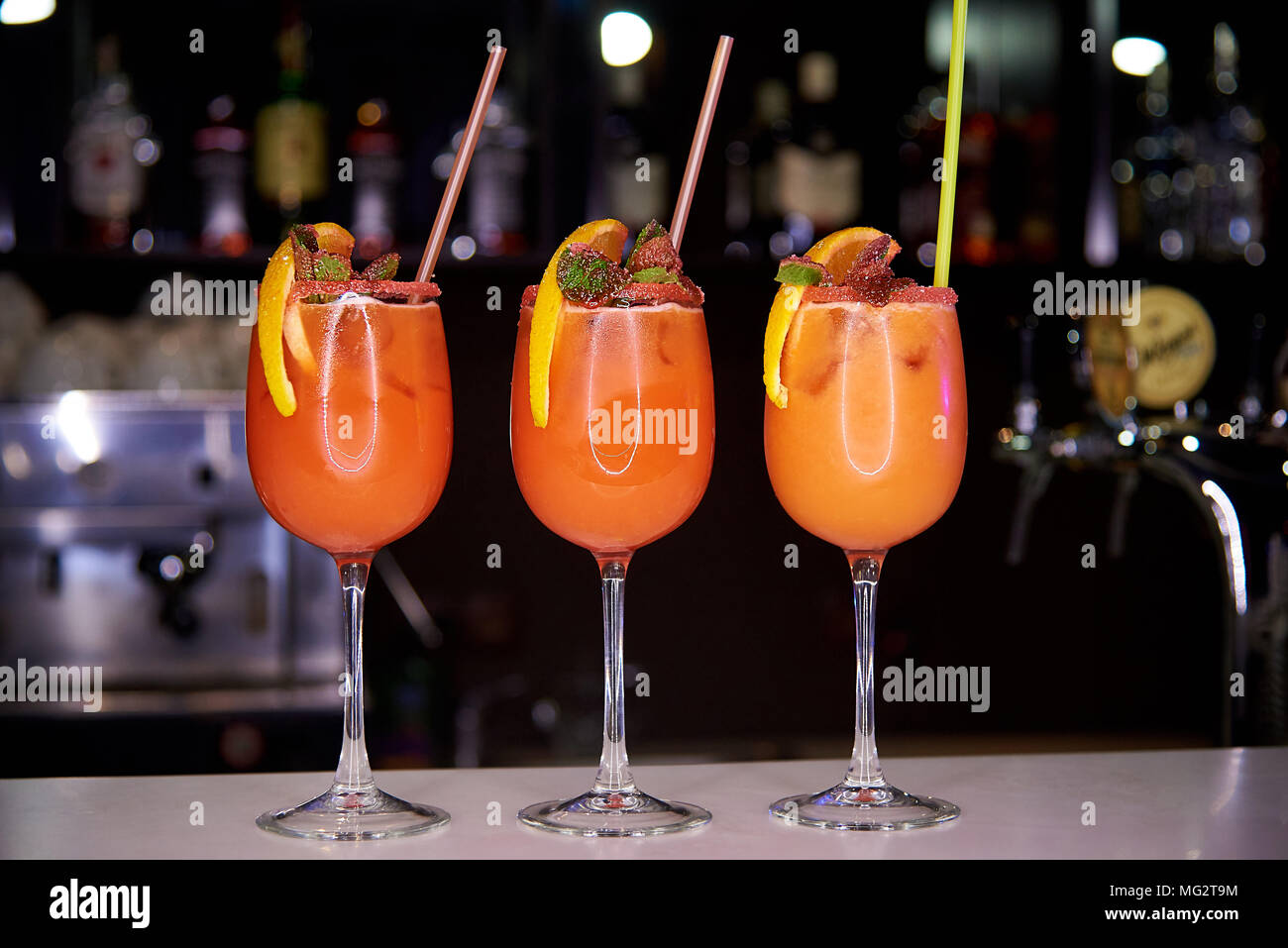 Three orange cold cocktails decorated with sugar crumbs, a slice of orange and mint on the bar in the restaurant Stock Photo