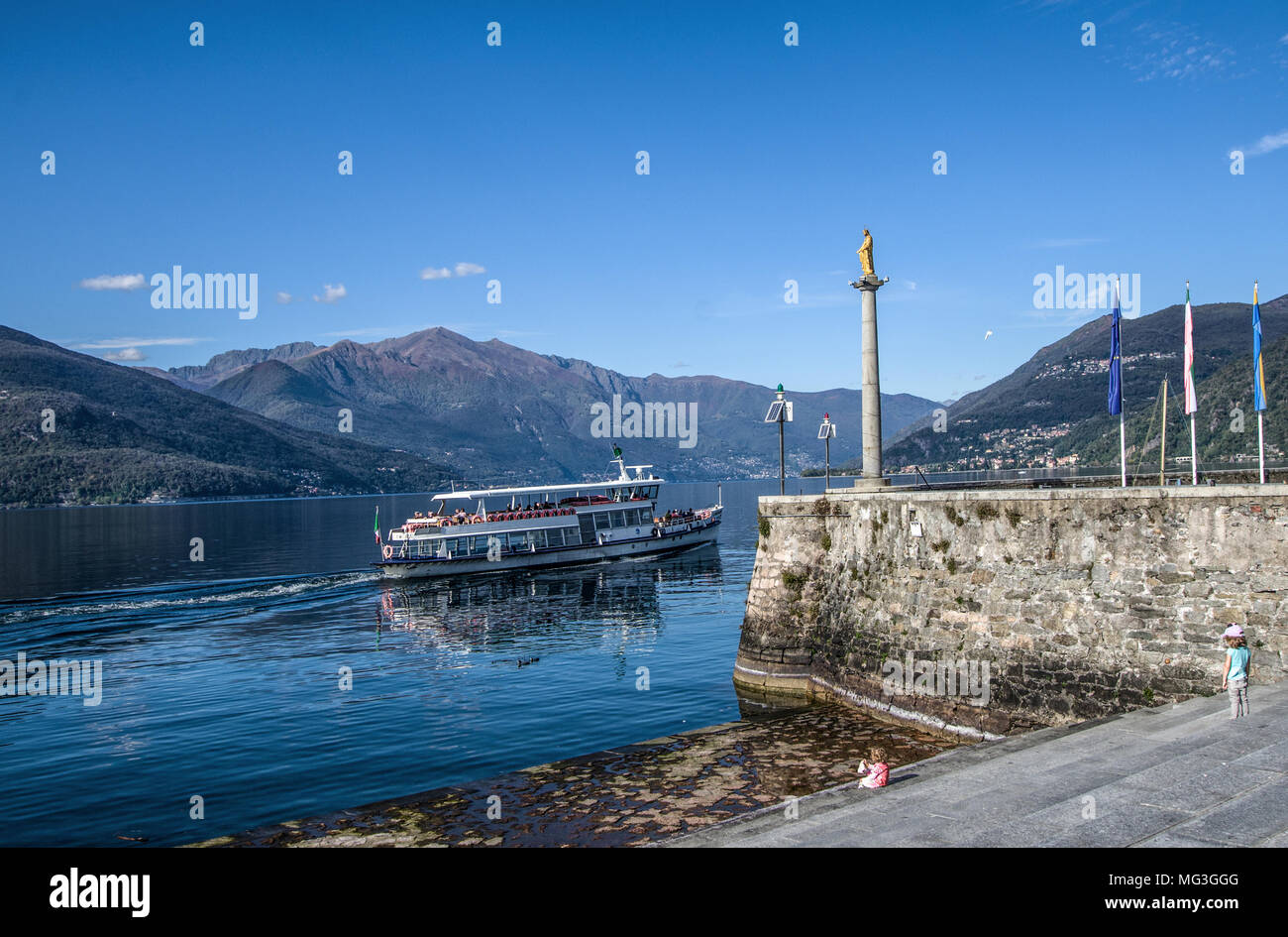 a boat sailing in front of the little port of the Madonnina, on Lake Maggiore.Luino, Italy Stock Photo