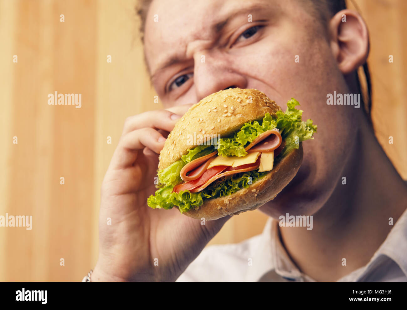 the young guy is really trying to burger and looking at camera Stock Photo