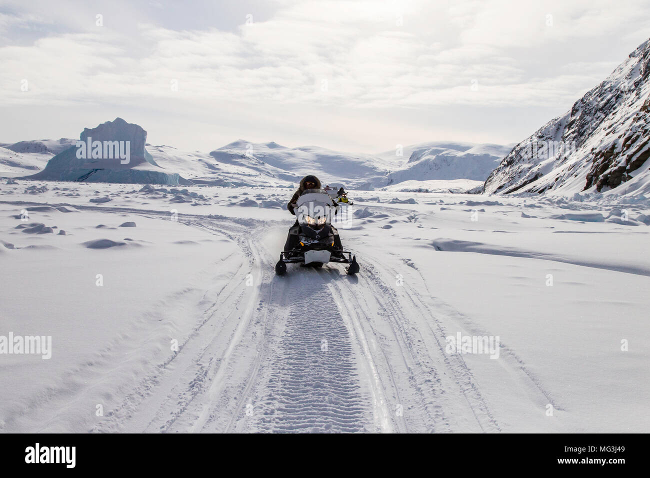 Solitary ski doo rides over a frozen fjord.  Baffin Island, Nunavut, Canada, arctic Stock Photo