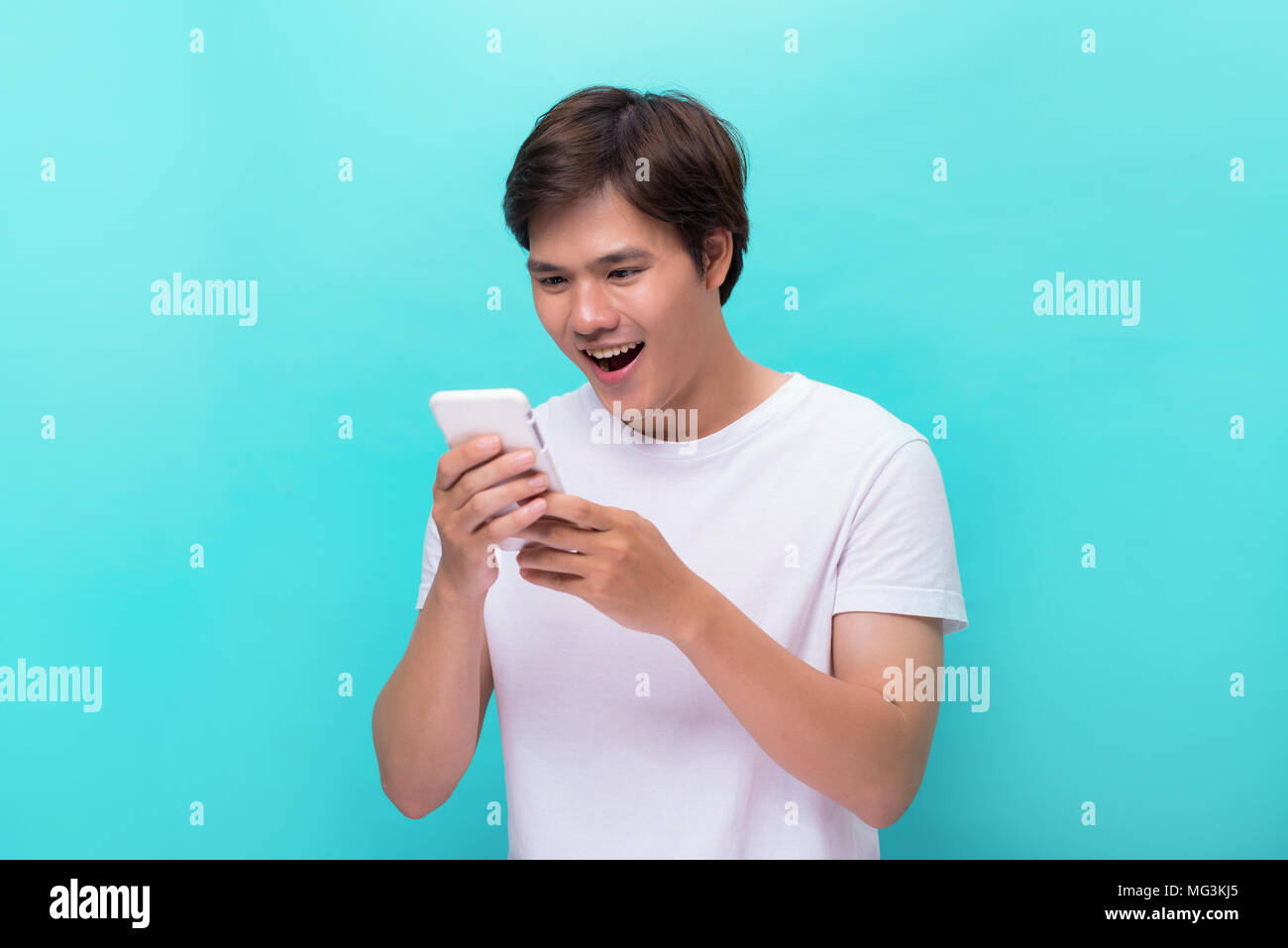 Happy asian man reading funny text on mobile. Stock Photo