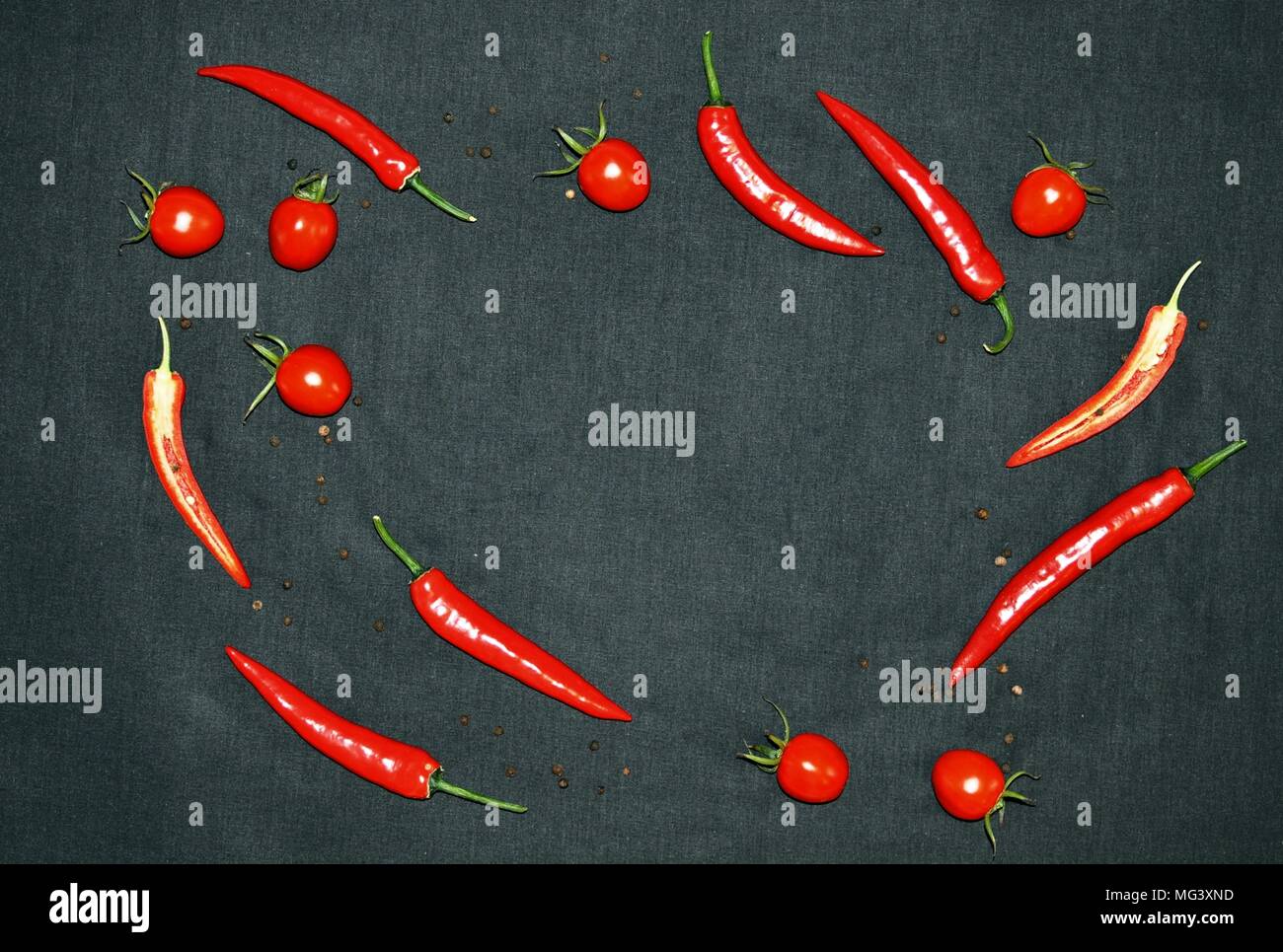 Hot chilli, pepper and cherry tomatoes on black background, top view, minimalist roundly style, copy space Stock Photo