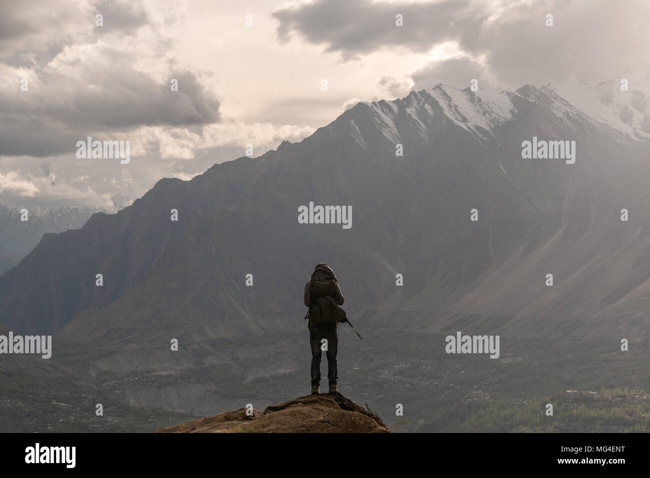 Traveller with backpack standing on mountain peak. Travel lifestyle and achievement success concept Stock Photo