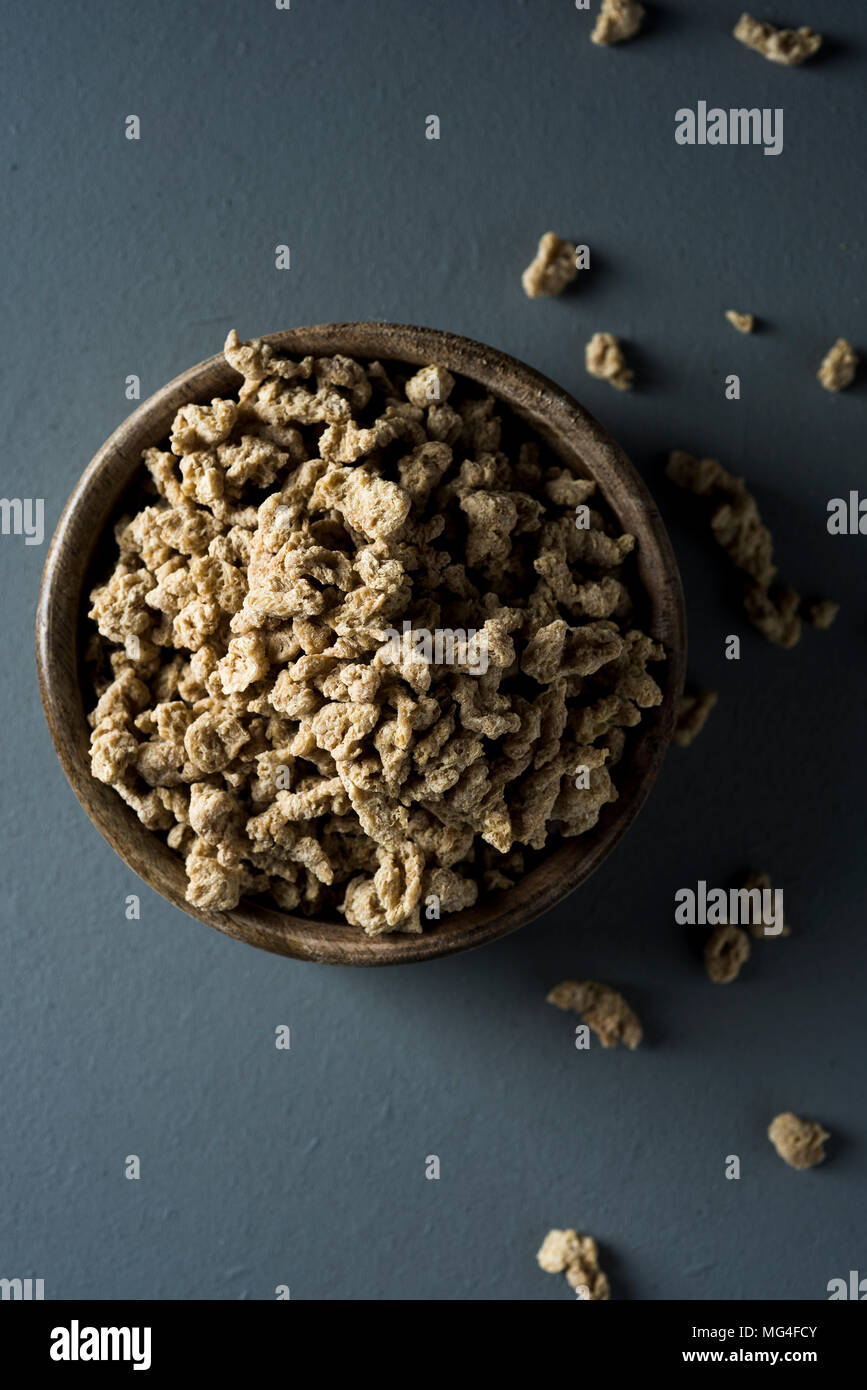 high angle view of some chunks of textured soy protein in a rustic boxwood bowl, placed on a gray wooden table Stock Photo