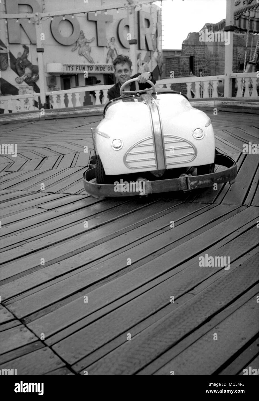 A teenager enjoys a ride on the dodgems at a funfair somewhere in the UK on a cold day in the 1950s Stock Photo