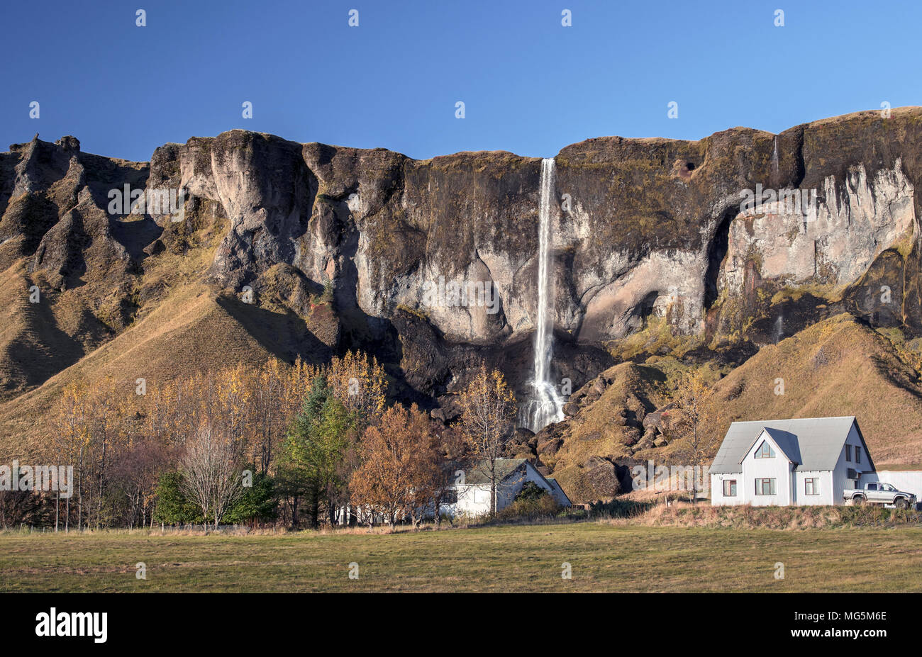 Waterfall behind Icelandic house Stock Photo